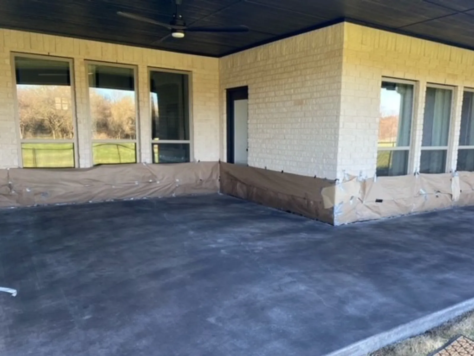 Black Antiquing Stain sprayed across a smooth covered concrete patio before applying the topcoat.