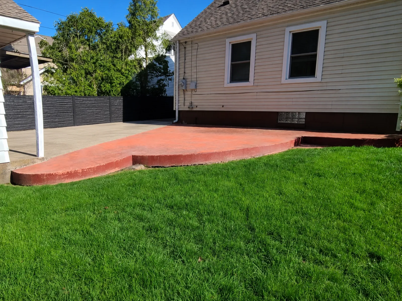 Faded red stamped concrete patio before restoration with Black and Charcoal Antiquing Stain.