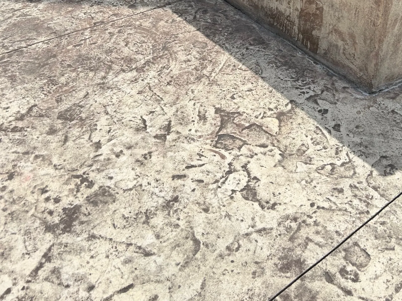 Close-up of a severely faded stamped concrete patio before applying Cumin Antiquing Stain.