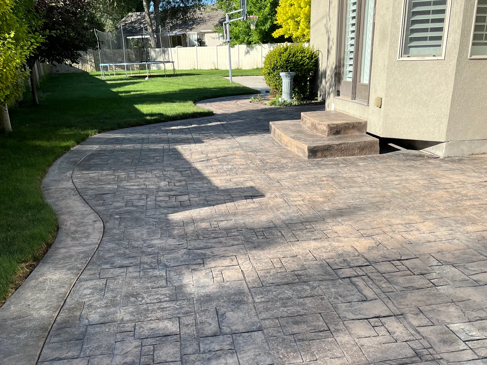 Faded and weathered 11-year-old stamped concrete patio before applying Chocolate EasyTint.
