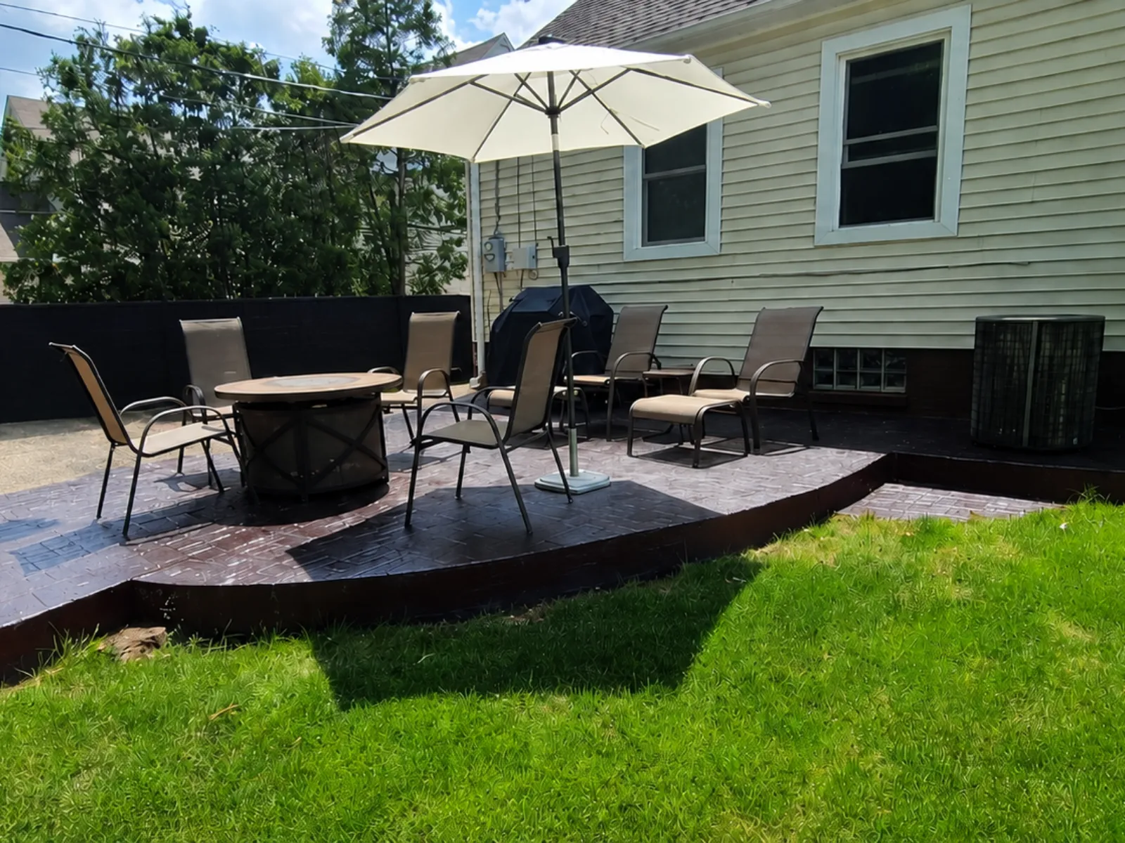 Backyard stamped concrete patio restored with Black and Charcoal Antiquing Stain and arranged with outdoor furniture