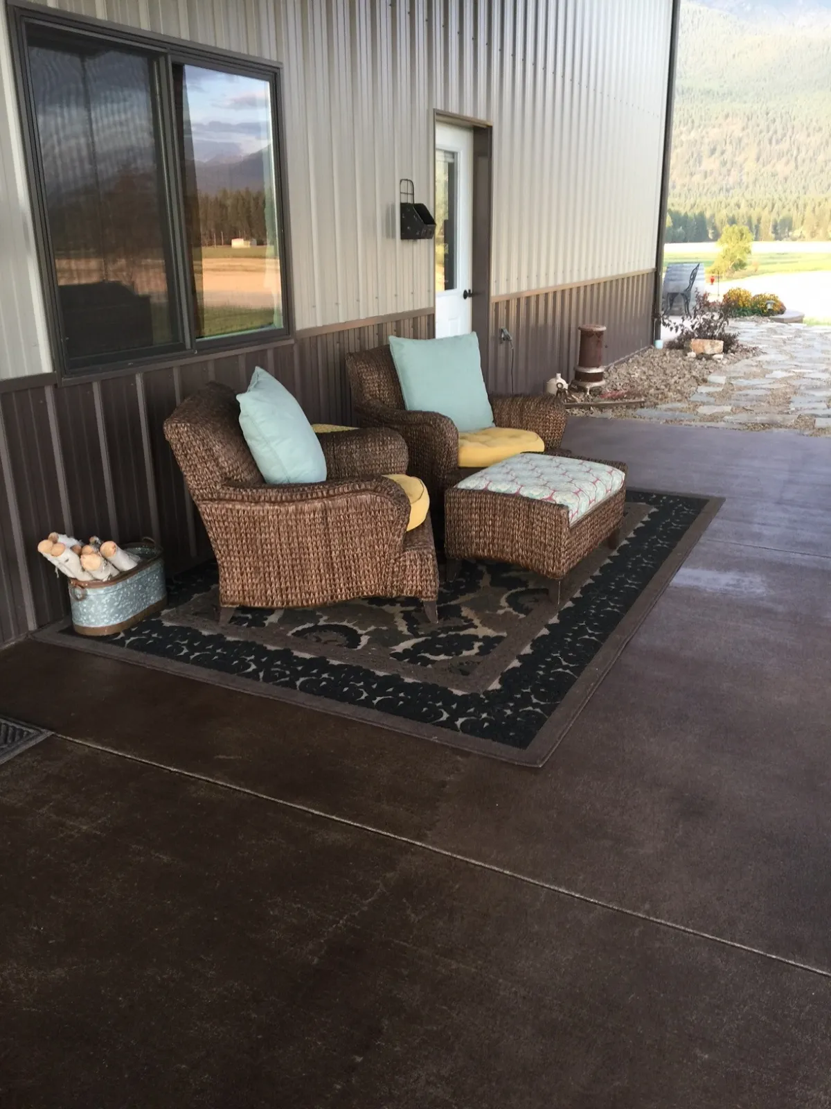 Covered pole barn concrete porch finished with variegated brown Driftwood Antiquing Stain and furnished with wicker seating.
