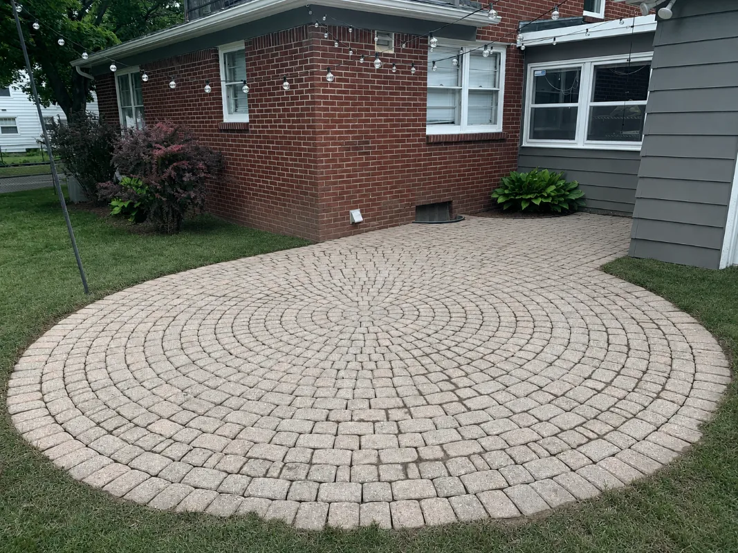 Dated pink concrete paver patio in a circular cobblestone pattern before whitewashing with PaveWave White