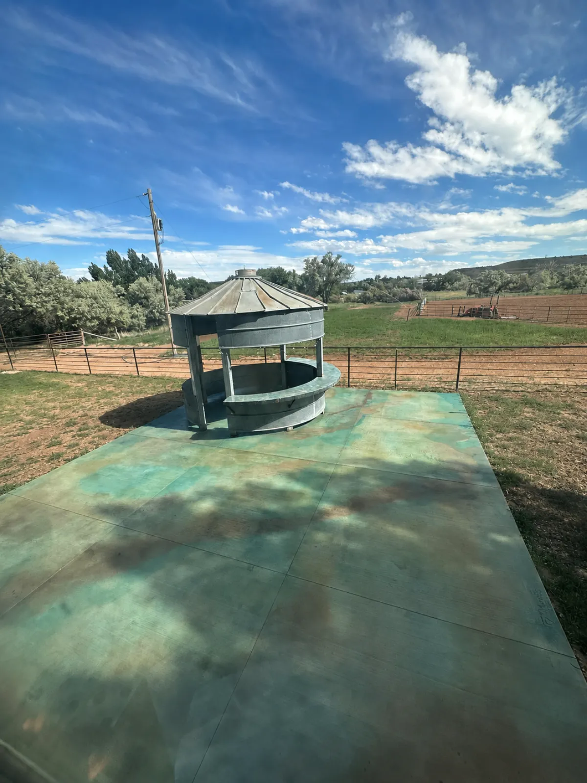 Concrete patio acid stained in turquoise and rust with Azure Blue and Coffee Brown EverStain, beside a repurposed grain-bin bar on a ranch