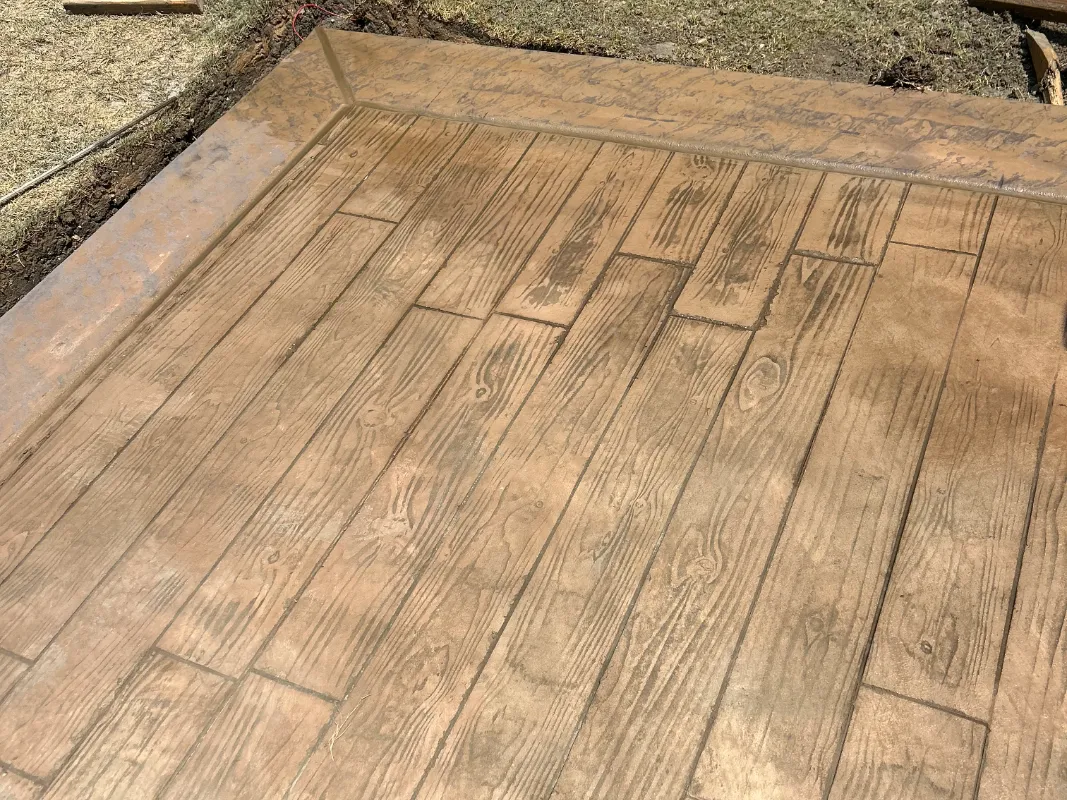 Freshly stamped wood-plank concrete patio in a plain wheat integral color before Antiquing stain